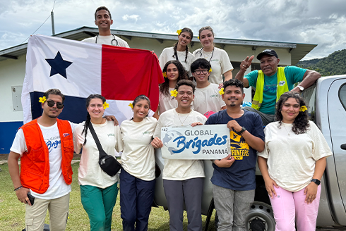 Large group of people standing on or below truck, someone holding a panama flag, while someone in the middle is holding a sign that says 