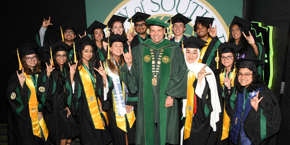 Graduates smiling around USF President Limayem