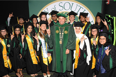 Graduates smiling around USF President Limayem