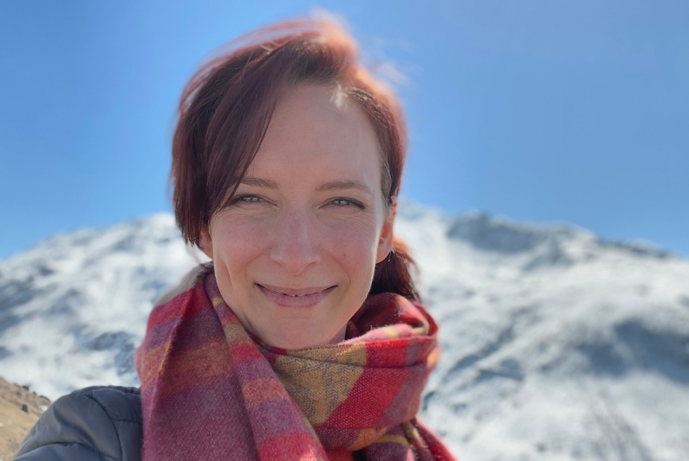 Laura smiles with a snowy mountain behind her