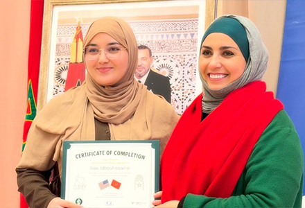 Two people smiling while holding a certificate