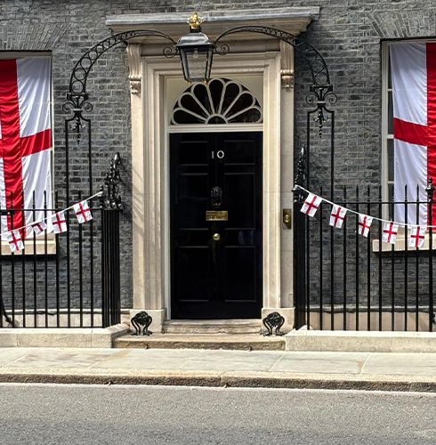 A large wood door with white and red cross flags hanging over it