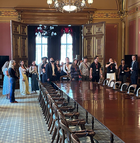 Group of people smiling in a long ornate room