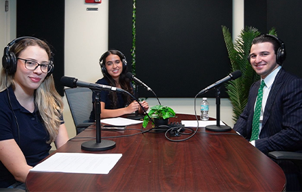 Richter sitting with two other people smiling in front of a mic at the table