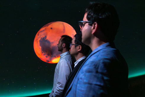 people in white doctor coats staring at a planet in the background