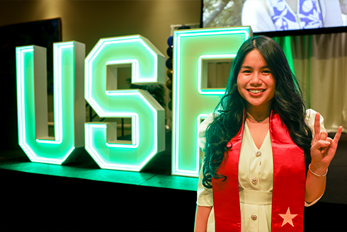 Bui smiling in front of a glowing neon